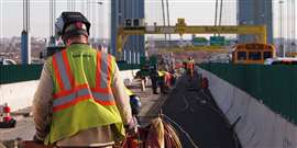 A Tutor Perini worker in branded workwear with his back to the camera on a construction site